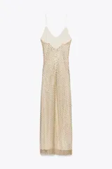 Vestido largo color dorado, confeccionado en tejido tipo red con aplicación de strass, escote pico y tirantes finos. Incluye forro interior y cierre en espalda con cremallera oculta en costura.