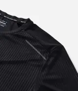 Remera deportiva de manga corta y cuello redondo, color beige claro, con textura acanalada vertical. Presenta detalles reflectantes en los hombros.