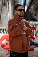 Buzo marrón con cierre medio, cuello alto y corte oversize. Estampado frontal con el número 19, un ancla con laureles y la frase "Refuse to Lose".