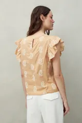 Blusa color beige con estampado paisley blanco, cuello redondo y mangas cortas con volados.