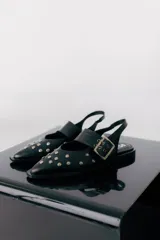 Chatas color marrón con punta fina, tira sobre el empeine con hebilla y detalle de tachas plateadas.