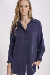 Camisa color verde oliva, de corte recto, con cuello camisero y mangas largas con puños abotonados.