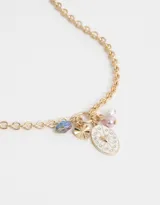 Collar corto dorado con cadena de eslabones gruesos y dijes colgantes: cristal facetado azul, dije dorado con forma de abanico, dije ovalado blanco con corazón dorado y strass, perla rosa y perla blanca.