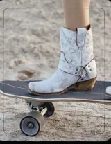 Bota corta de cuero color marrón, con taco de madera y punta cuadrada. Presenta una correa con hebilla alrededor del tobillo.