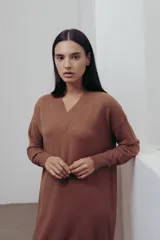 Vestido negro tejido con escote en V y corte recto. Largo hasta la rodilla con tajos laterales y detalle canalé en puños y ruedo.