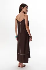 Vestido largo color crudo con breteles finos y costuras a la vista en color azul.