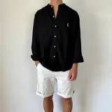 Camisa blanca de lino con cuello mao, manga larga y corte regular. Presenta un pequeño bordado en el pecho.