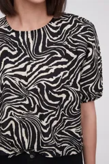 Blusa con estampado animal print en blanco y negro, de mangas cortas abullonadas y cuello redondo.