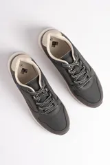 Zapatillas deportivas grises con cordones blancos y suela color crema.