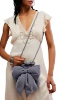 Bolso de terciopelo negro, estilo saco o fruncido, con un gran lazo decorativo en el frente. Posee una correa de hombro ajustable con herrajes dorados.