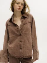 Campera de denim gastado color celeste, con cuello camisero, corte holgado y canesú con costuras delante y atrás.