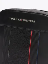 Bandolera Tommy Hilfiger negra con correa ajustable, cierre de cremallera, bolsillo interior abierto y logo metálico en el frente.