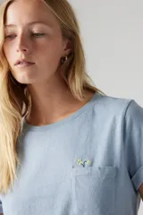 Remera celeste de algodón con bolsillo en el pecho y pequeño bordado de flores.