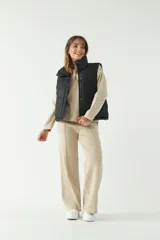 Chaleco puffer color verde oliva con cuello alto y cierre frontal con cremallera.