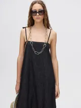 Vestido midi de denim algodón color marrón, con escote recto y tirantes finos ajustables con lazos. El corte es suelto y termina con un ruedo con semi-volado.