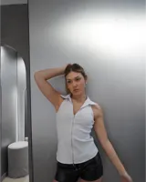 Top blanco sin mangas con cuello polo y cierre frontal con cremallera.