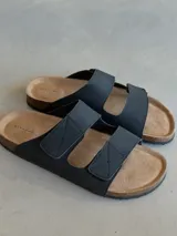 Sandalias negras con dos tiras anchas con costuras en forma de X, plantilla de corcho y suela de goma.