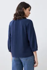 Blusa color crudo con escote en V y mangas largas.