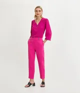 Pantalón zanahoria de crepé color fucsia, con cintura alta, bolsillos laterales y cierre frontal con botones.