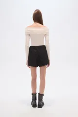 Short de jean color beige claro, tiro alto, corte ajustado y diseño cruzado con botones dorados decorativos en el lateral.