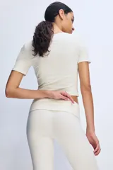 Remera cropped blanca de punto acanalado fino de algodón, con escote amplio en U y mangas cortas. De ajuste entallado y bajo recto.