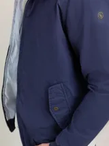 Cazadora tipo bomber color beige, con cierre frontal y bolsillos de solapa.