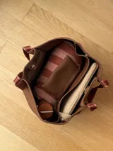 Bolso negro tipo tote de neopreno con bolsillo interno de red, sobre haciendo juego y gancho para sujetarlo.