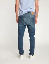 Pantalón de jean azul con roturas en las rodillas, corte slim fit.