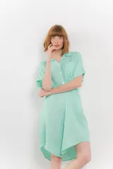 Vestido camisero corto color verde agua, confeccionado en lino 100%. Tiene botones en la parte delantera, cuello camisero, mangas cortas con botón para arremangar y bolsillos laterales.