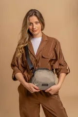 Bandolera pequeña de tela negra, con correa ancha ajustable y cierre superior.