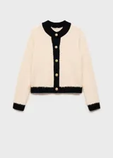 Chaqueta de punto color crema con terminaciones en contraste negro, cuello redondo, diseño recto, cierre delantero con botones dorados y manga larga.