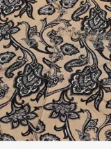 Bufanda rectangular color beige con estampado floral en negro y flecos pequeños en los extremos.