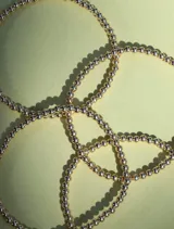 Pulsera elástica compuesta por cuentas redondas pequeñas de 3mm, con acabado dorado.