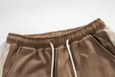 Pantalón de estilo babucha/jogging, color azul oscuro, confeccionado en tela tipo gamuza suave. Presenta una guarda lateral blanca y cintura elástica con cordón regulable. Cuenta con tres bolsillos: dos delanteros y uno trasero.