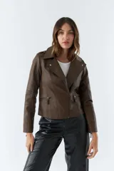 Campera marrón de cuero sintético, estilo motociclista, con cuello solapa, cierre asimétrico, bolsillos con cierre y detalles de costuras en los hombros y mangas.