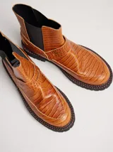 Bota Chelsea de cuero negro con estampado de cocodrilo, elástico lateral y suela de goma con pespuntes azules.