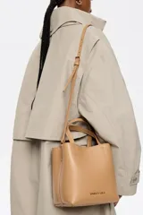 Bolso tote pequeño de piel reconstituida color gris claro, con estructura rígida, doble asa corta, correa extraíble, cierre con botón de presión, logo metálico BIMBA Y LOLA, acabados metálicos, bolsillo interior con cierre de cremallera e interior con logo grabado.