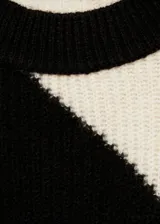 Sweater de punto con diseño de rayas diagonales en blanco y negro, de corte holgado y cuello redondo.