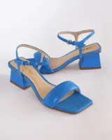 Sandalias de cuero azul satinado con tira principal acolchada y taco piramidal de 6 cm.