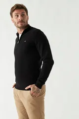 Sweater de punto negro con cuello alto y cierre parcial con cremallera.