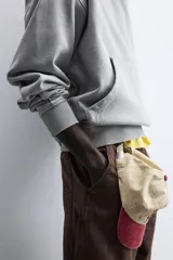 Sudadera gris con capucha ajustable, corte boxy fit, manga larga, bolsillo tipo canguro y estampado en la espalda.