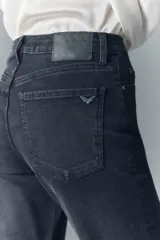 Pantalón de jean negro de tiro medio, corte ajustado en la cintura y muslos, y acampanado desde la rodilla hasta el ruedo. Confeccionado en tejido confort con elastano, cierre y botón.