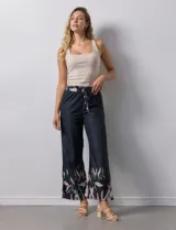 Pantalón negro con estampado de hojas color rosa en el ruedo y cintura elastizada con lazo ajustable.