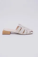 Mules color crudo con capellada trenzada de cuero y taco de madera de 3 cm.
