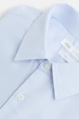 Camisa celeste de algodón, corte regular fit, con cuello italiano, manga larga con puños abotonados y cierre frontal con botones.