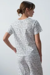 Conjunto de pijama blanco con estampado de corazones negros, compuesto por una remera de manga corta con bolsillo en el pecho y un pantalón largo de corte recto.