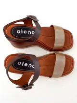 Sandalias de cuero color marrón con plataforma y tira delantera dorada. Tira trasera marrón con hebilla metálica.