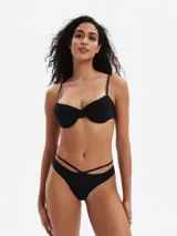 Conjunto de bikini negro, con corpiño tipo push-up con tirantes finos y bombacha de corte bajo con tiras cruzadas en la cintura.
