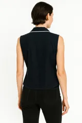 Camisa blanca sin mangas, con cuello clásico, corte al cuerpo y vivos negros en cuello y botones.