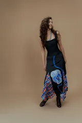 Falda larga negra con estampado de flores y diseño irregular con tajos y paneles de tela estampada a cuadros en tonos rojo, azul y blanco.